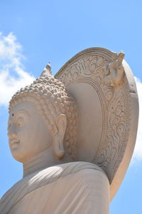 Low angle view of buddha statue against sky