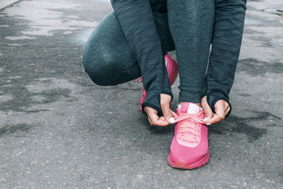 Low section of woman tying running shoes