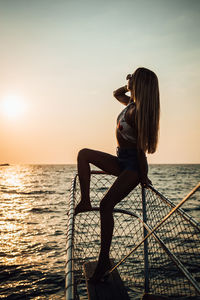 Woman on boat in sea against sky during sunset