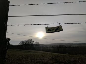 Low angle view of hanging lights against sky during sunset