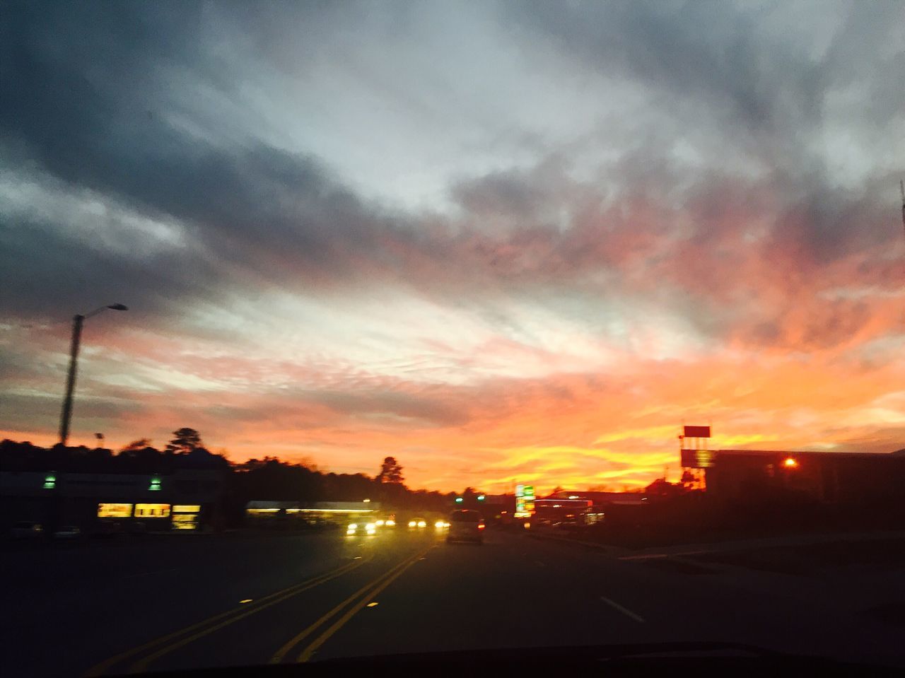 sunset, sky, silhouette, cloud - sky, transportation, road, orange color, street light, car, illuminated, land vehicle, street, dramatic sky, cloudy, dusk, cloud, mode of transport, building exterior, built structure, outdoors