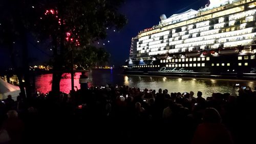 Crowd at illuminated city against sky at night