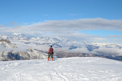 Rear view hiker on snowcapped mountain against sky