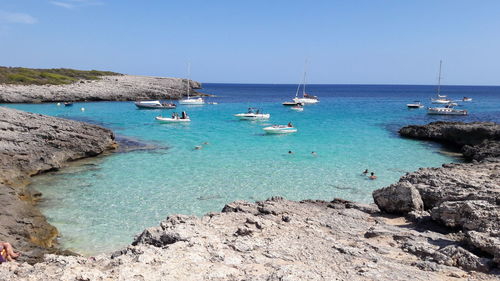 Sailboats moored on sea against clear blue sky