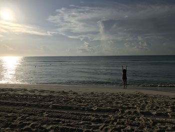 Man standing on beach against sky during sunset