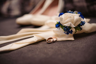 Close-up of rose made from ribbon by wedding rings on table