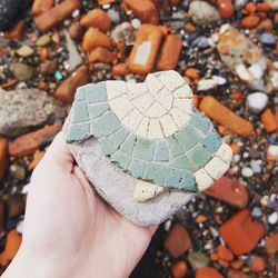 Cropped image of hand holding damaged stone at beach