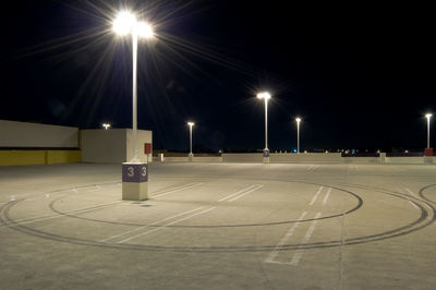 Illuminated street lights against sky at night