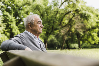 Smiling senior man sitting on a bench in nature