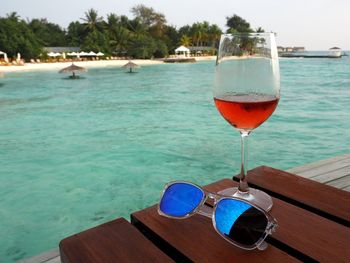 Close-up of beer on table by swimming pool against sea