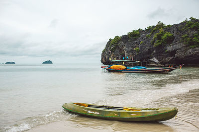 Boats moored on sea shore against sky