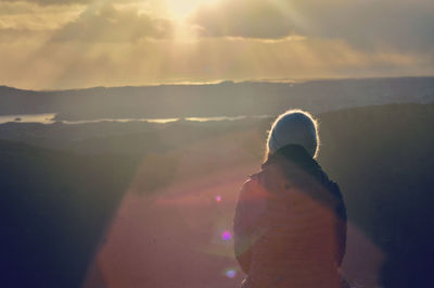 Rear view of man standing against sky during sunset