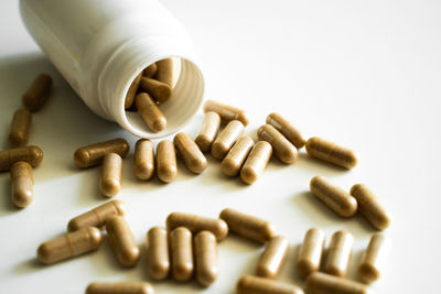 Pills spilling from bottle against white background