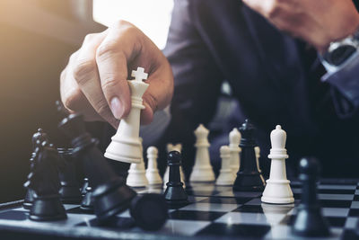 Midsection of businessman playing chess at table