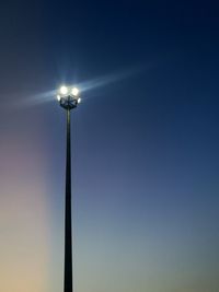 Low angle view of illuminated floodlight against blue sky