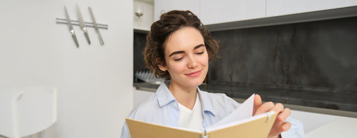Portrait of smiling young woman using digital tablet while standing at home