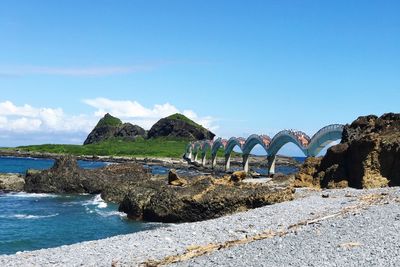Arch bridge over sea against blue sky