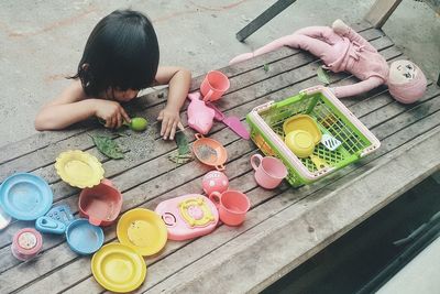High angle view of girl playing with toys on wooden table at yard