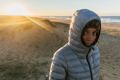 Portrait of woman standing at beach during sunset