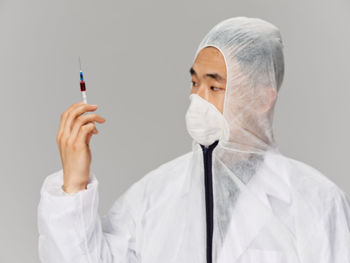 Portrait of young woman holding syringe against white background