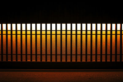 Close-up of railing against window at sunset