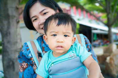 Portrait of cute smiling son with mother sitting outdoors