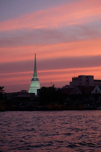 Building by sea against sky during sunset