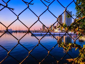 Scenic view of river seen through chainlink fence against sky