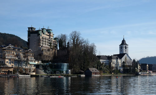 Buildings by river against sky