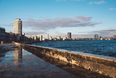 Sea by buildings against sky in city