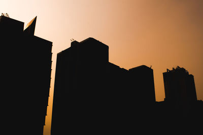 Low angle view of silhouette buildings against sky during sunset