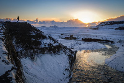 Hiker standing on mountain against sky during sunset