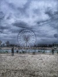 Ferris wheel on beach against sky