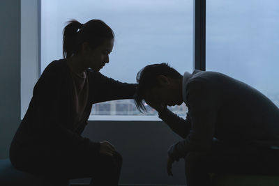 Woman consoling man while sitting by window