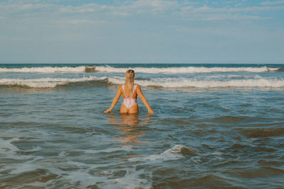 Rear view of woman standing at beach