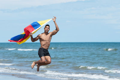 Full length of shirtless man in sea against sky