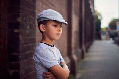 Close-up of cute boy wearing hat standing by building outdoors