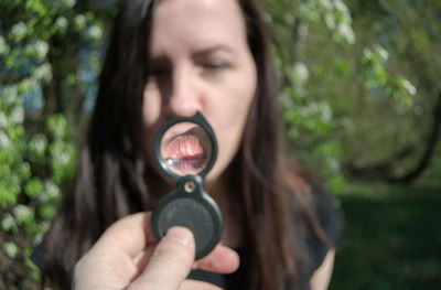 Cropped image of hand holding magnifying glass against woman puckering lips