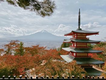 Traditional building by mountains against sky during winter