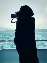 Side view of person photographing while standing in boat