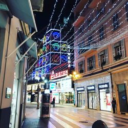 Illuminated street amidst buildings in city at night