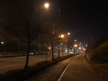 Illuminated road against sky at night