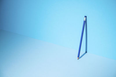Low angle view of colored pencils against blue sky
