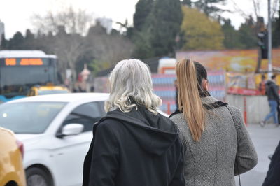 Rear view of man and woman walking on street in city