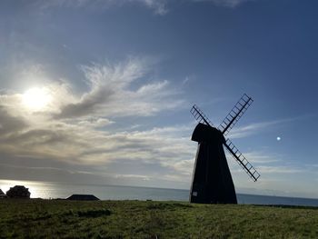 Traditional windmill on field against sky