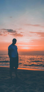 Rear view of man looking at sea during sunset