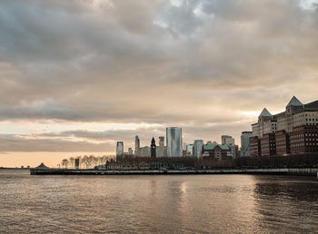 River by buildings against sky during sunset