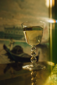 White wine drink in glass with stacked ball stem on gold brass table with image of venice 