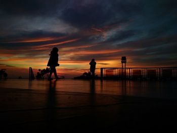 Silhouette people at walkway against sky during sunset