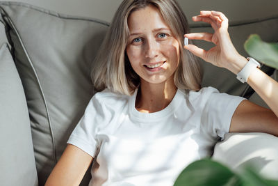 Portrait of young woman sitting on sofa at home